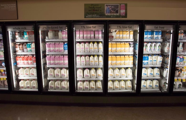 Grocery store fridges show a variety of dairy products.