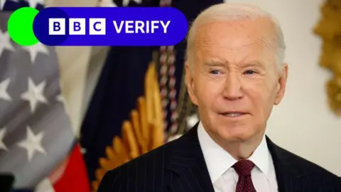 Getty Images Joe Biden speaks to reporters in the White House. An American flag is visible in the background, and the BBC Verify logo has been imposed over the image. 