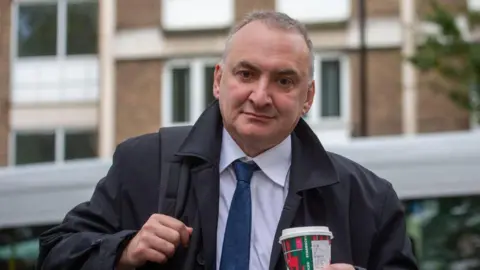 Alamy Chris Wormald holding a coffee cup as he arrives at the Covid inquiry in London