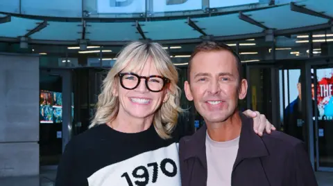 Zoe Ball and Scott Mill pictured smiling outside the BBC's New Broadcasting House in London