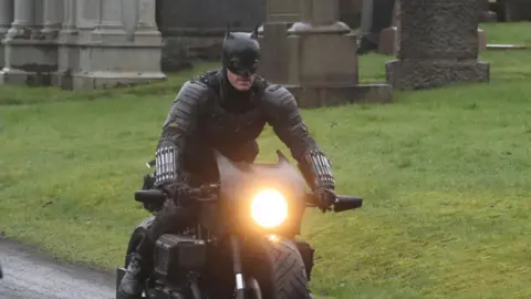 PA Media Batman riding his motorbike through a graveyard