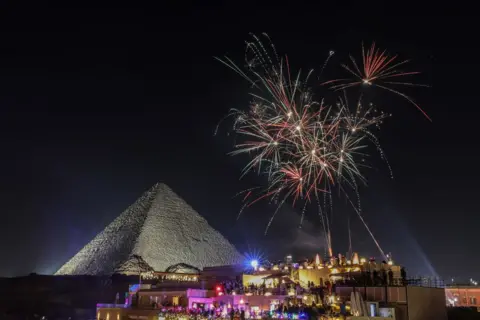 Mohamed Elshahed/Anadolu via Getty Images Fireworks light up the night sky to welcome the new year at the pyramids in Giza, Egypt - 1 January 2025. 