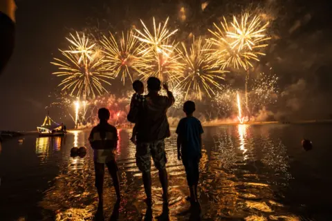 YASUYOSHI CHIBA/AFP Local residents watch fireworks over the city of Jakarta, as they celebrate the new year at nearby Ancol Beach in Indonesia, on 1 January 2025.