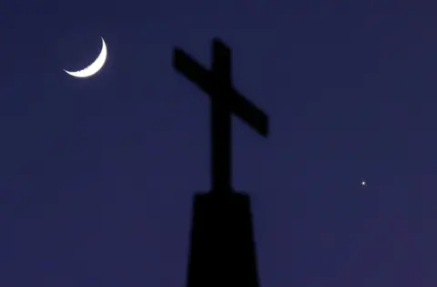 Reuters A crescent moon and the planet Venus straddle a cross on top of Quebec Baptist Church in Ellaville, Georgia