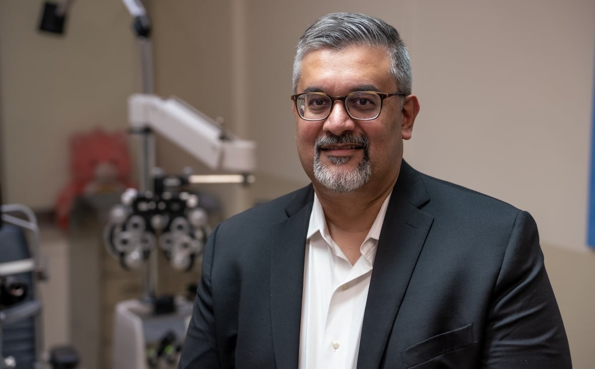 Photo of Dr. Asim Ali, with eye exam equipment in the background. 