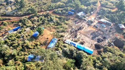 Defence PRO, Guwahati A patch of land with greenery, dotted by camps with blue, plastic sheds at the rescue site.