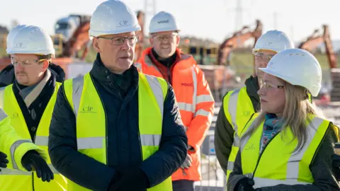 PA Media John Swinney wearing a yellow high-vis jacket and white hard hat with several similarly dressed members of the CIP team on the construction site at Coalburn 1