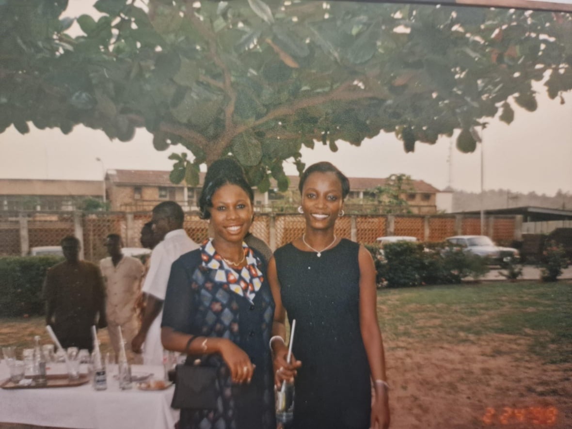 Two women pose for a photo with an African tree in the background.