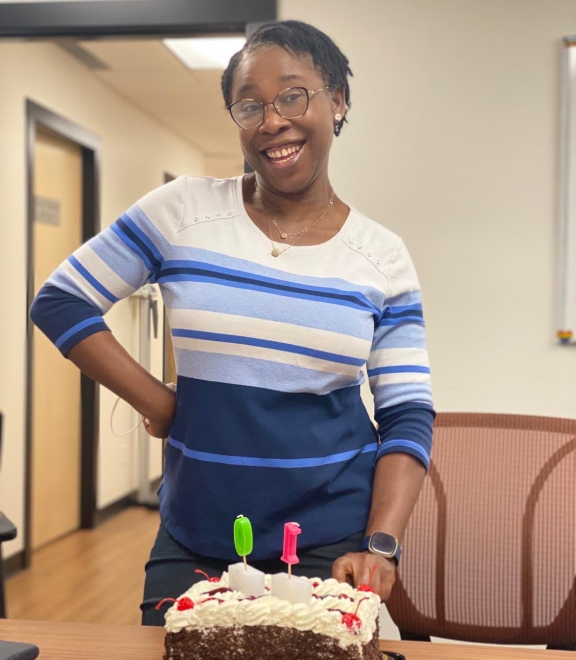 A woman stands behind a cake on a table.