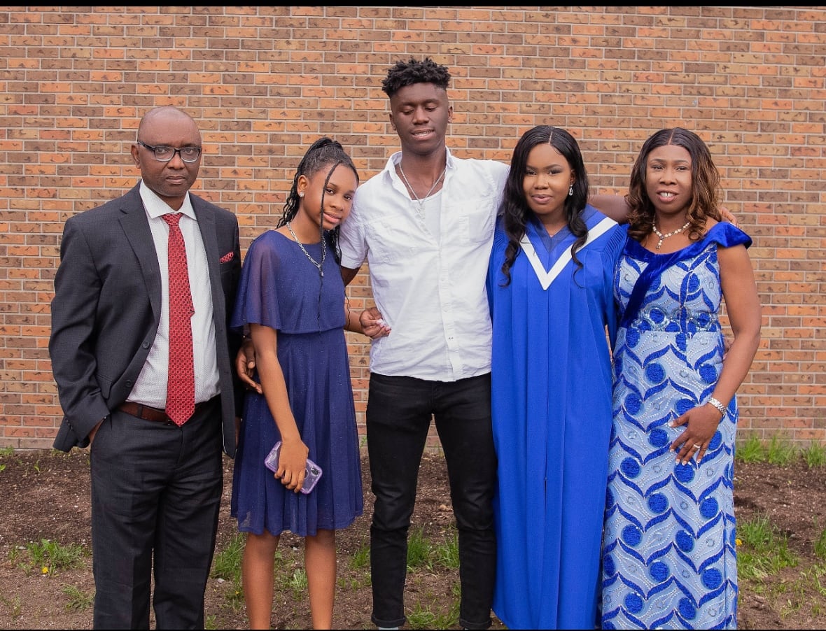 A family poses for a photo with one woman in a blue graduation robe.