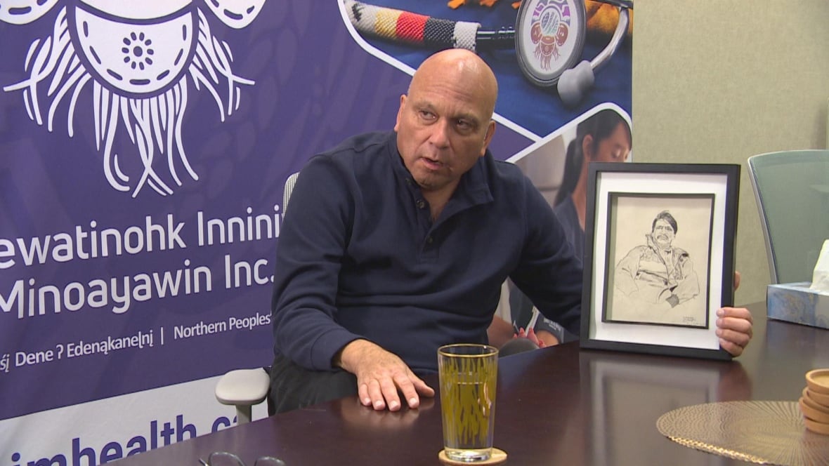 A man is holding a picture in front of a banner.