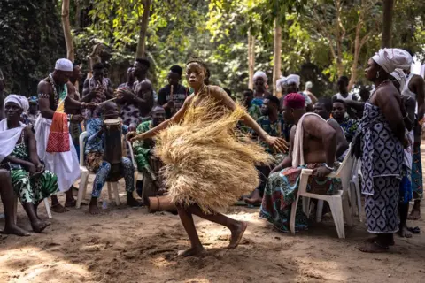 OLYMPIA DE MAISMONT/AFP A Voodoo devotee dances during a festival surrounded by people in a forest 