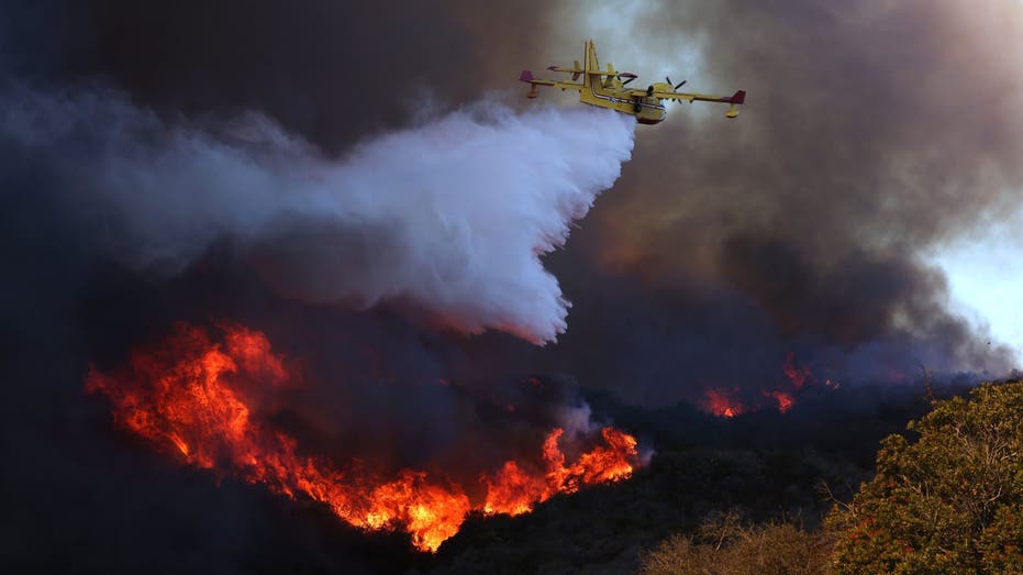 PACIFIC PALISADES, CALIF JANUARY 7, 2024 A firefighting plane makes a drop on the Palisades fire in Pacific Palisades on Tuesday, Jan. 7. The Palisades fire is being pushed by gusting Santa Ana winds that were expected to continue for two more days. (Brian van der Brug / Los Angeles Times via Getty Images)