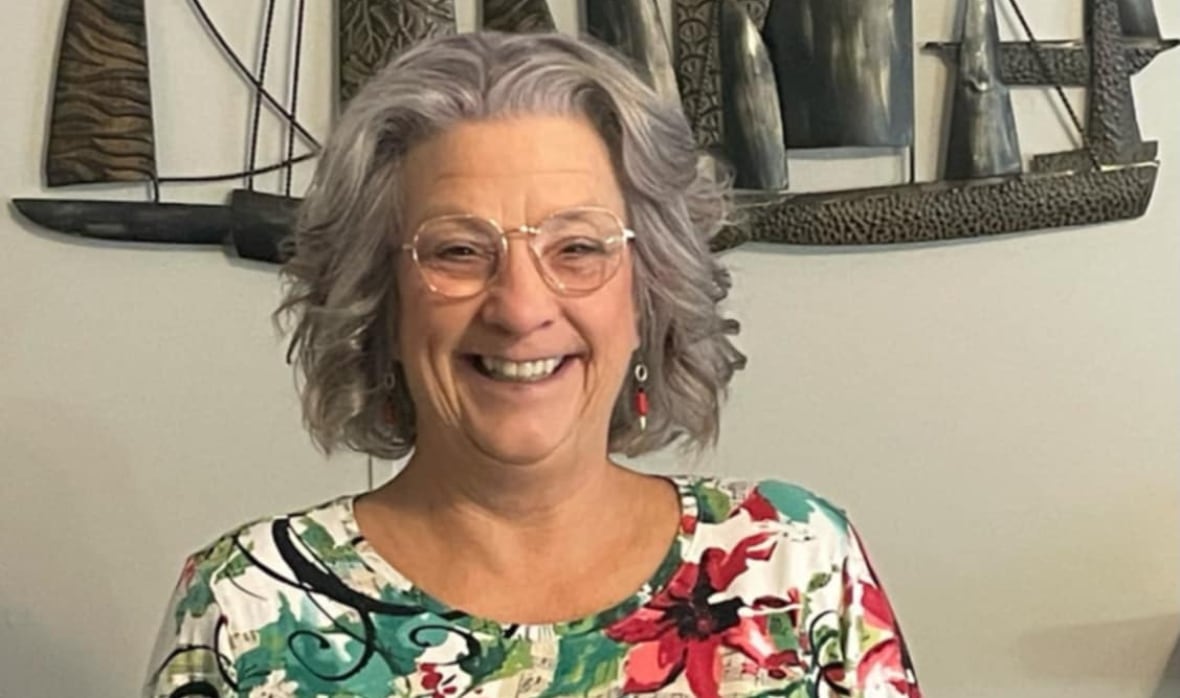 A woman with a colourful shirt is smiling.