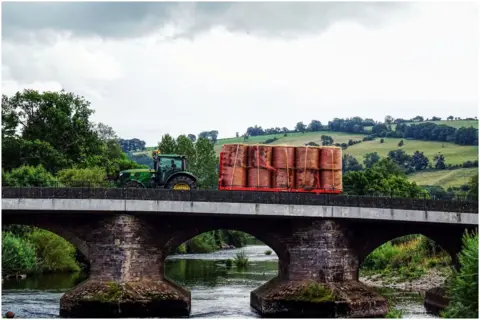 Julie Charles A tractor pulls a trailer of hay across a bridge