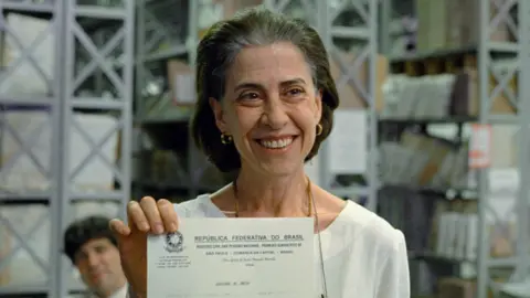 Altitude Films Eunice (played by Fernanda Torres) holding up her husband's death certificate