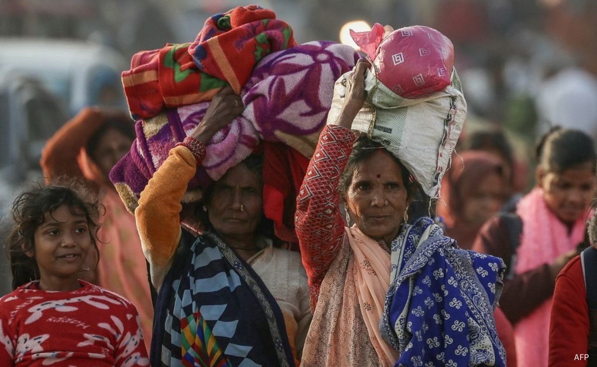 Pilgrims carrying their belongings arrive at Sangam