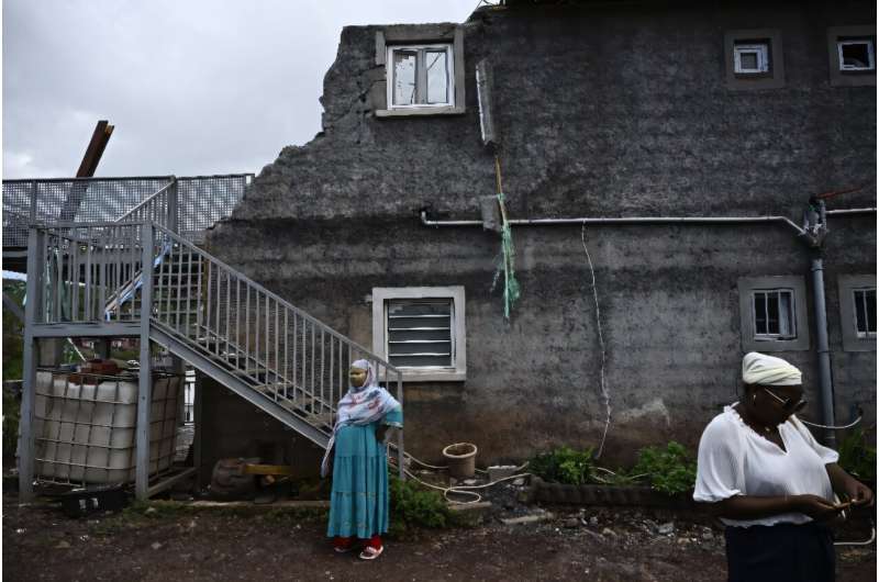 Local residents whose homes have been destroyed by Cyclone Chido stand in front of a damaged building on the French Indian Ocean territory of Mayotte