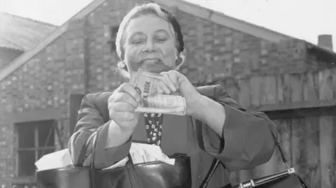 Getty Images Mrs Ann Smith of Wandsworth in south London tears up her ration book on the last day of rationing in 1954, which went on for 14 years during wartime. 