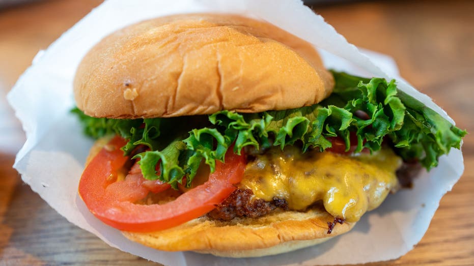 Close-up of a cheeseburger with tomato and lettuce in a paper wrapper at Shake Shack, Walnut Creek, California, August 25, 2024. (Photo by Smith Collection/Gado/Getty Images)