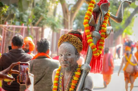 Ankit Srinivas An ash-smeared Hindu holy man holding a trident at the Kumbh Mela festival in Prayagraj in January 2025