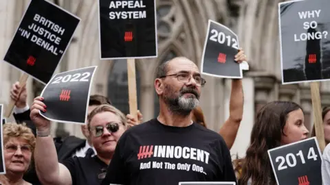 PA Media Andy Malkinson in a black T-shirt reading "Innocent" outside the Royal Courts following his appeal