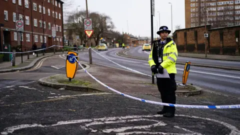 PA Media A police officer inside a police cordon on Woolwich Church Road in Woolwich