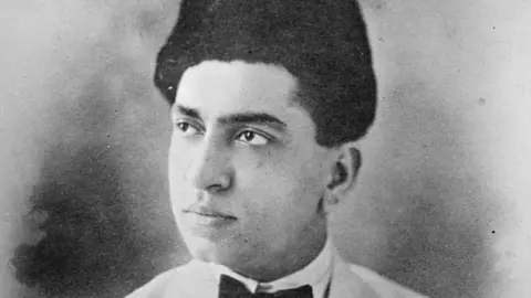 Alamy Abdul Kadir Bawla in a black-and-white photograph, wearing a suit with a bow tie and a traditional cap