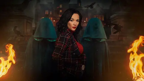 BBC Charlotte Chilton is pictured in a promo for The Traitors. She is looking at the camera side-on, with two figures in green hoods behind her. They are all stood in front of the steps up to a castle, with flames to the left and right of them.