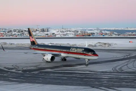 Getty Images Donald Trump Jr's plane, emblazoned with 'Trump' across the front, at Greenland's Nuuk airport. Ice can be seen on the runway and a snowy landscape behind.