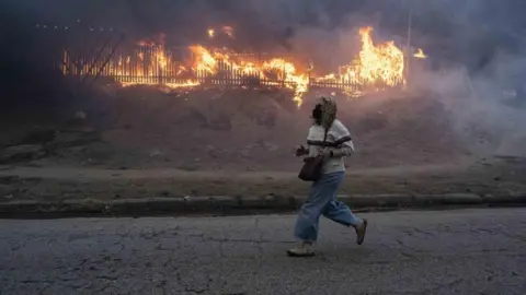 Getty Images A person runs past a building on fire