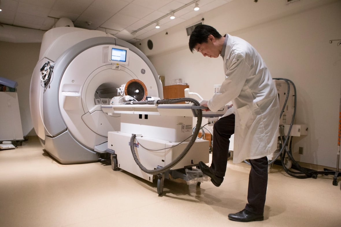 A man stands next to an MRI machine.