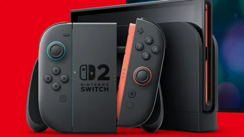 Nintendo A black Nintendo Joycon controller and console displayed against a bright red background. The central panel has a Nintendo Switch logo with a large numeral 2 alongside it. One of the joycons is detached from the main joypad unit, showing a red connector trim.