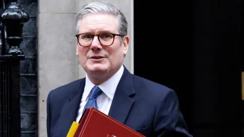 EPA Sir Keir Starmer outside Downing Street - he is wearing glasses, a blue suit, white shirt and light blue tie and is carrying a red folder