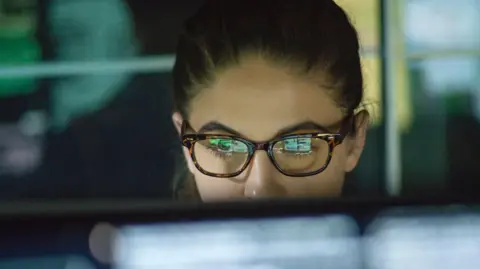 Getty Images Stock image of woman looking at computer with screen image reflected on her glasses