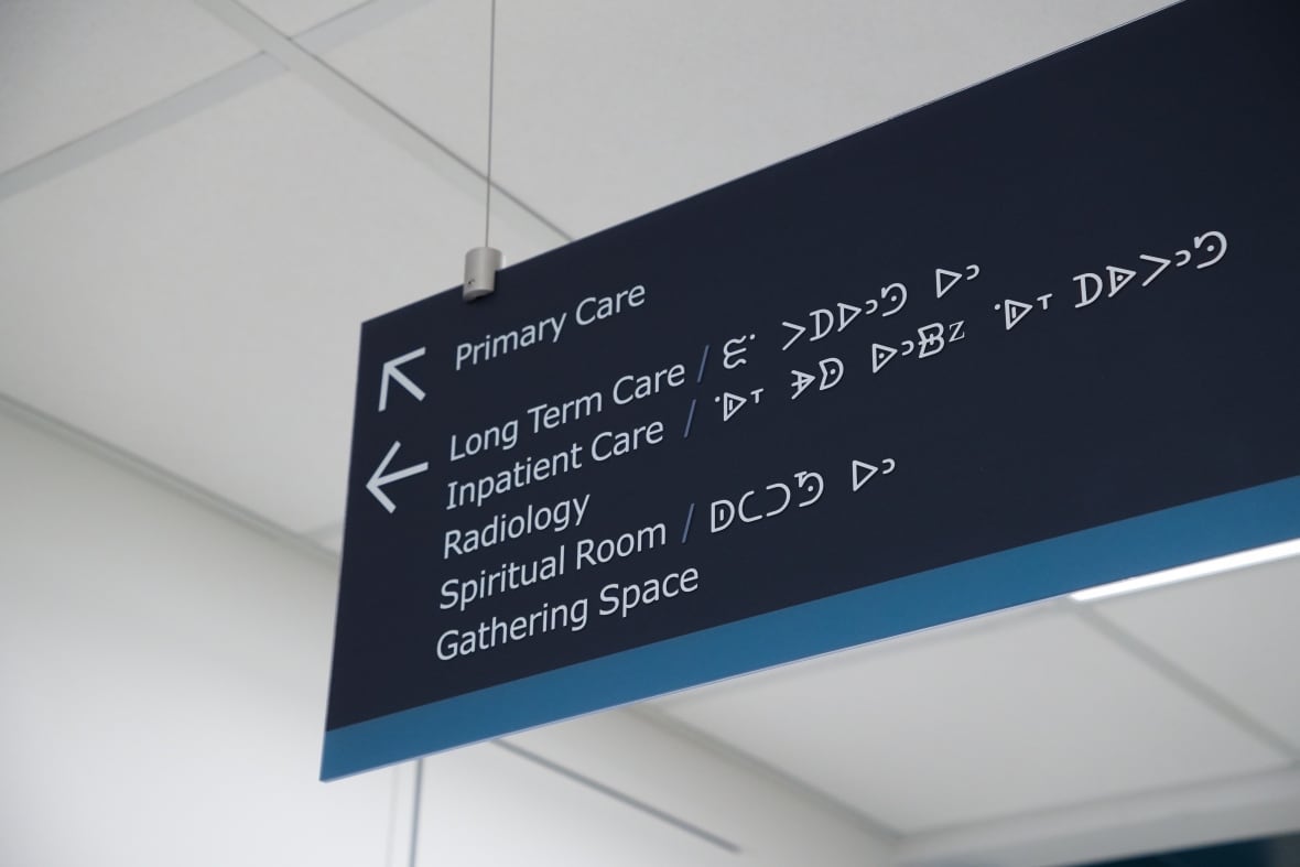 A sign pointing people to various areas of the hospital has wording in English and Dakelh.