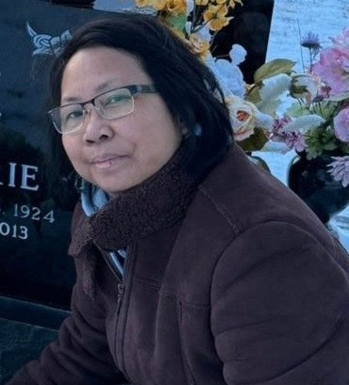 A woman looks at the camera by a grave