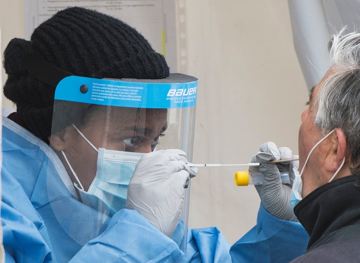 A health-care worker prepares to swab a man at a walk-in COVID-19 test clinic